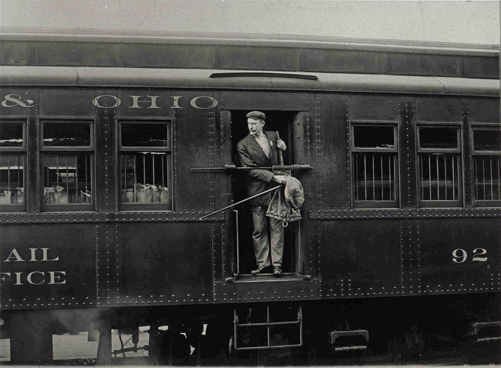 1024px-Railway_Post_Office_Clerk_in_Mail_Car.jpg